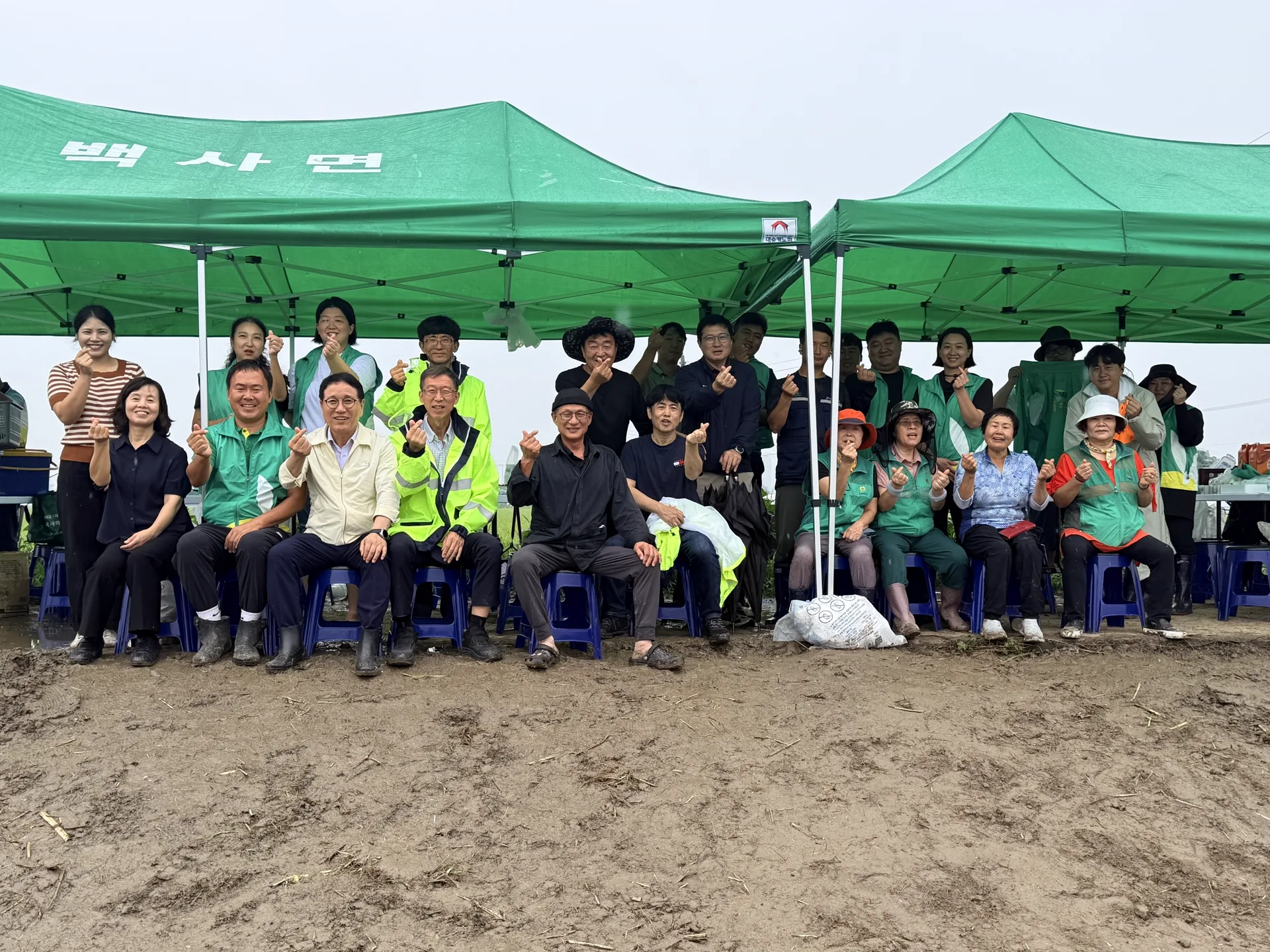 배추밭 옆 천막 아래 모여 앉은 청년새마을연대 회원과 마을 어르신 단체사진